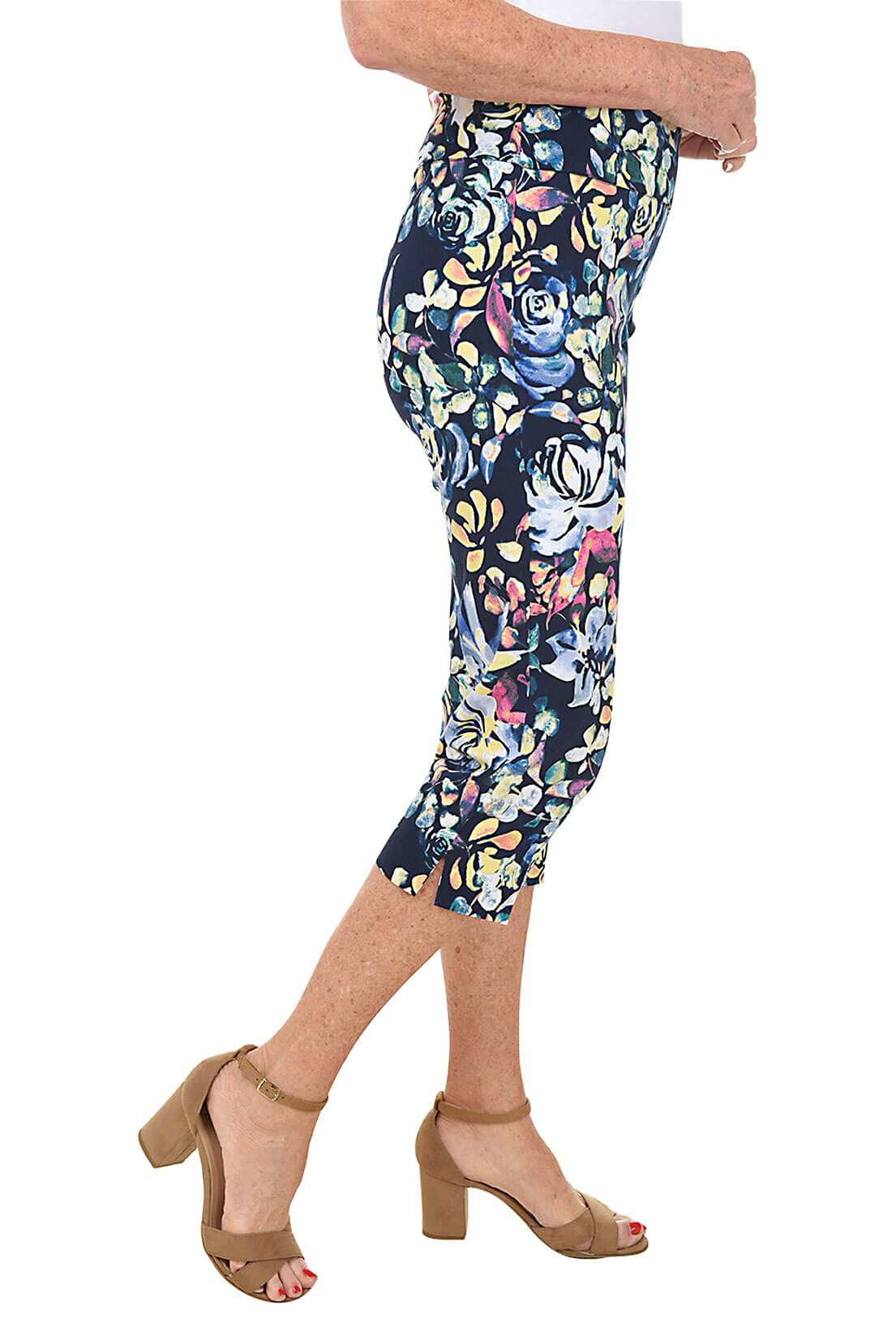 A side shot of a model wearing a pair of petite rose petal print pull-on crop pants with an elastic waistband and a side slit on the hemline.