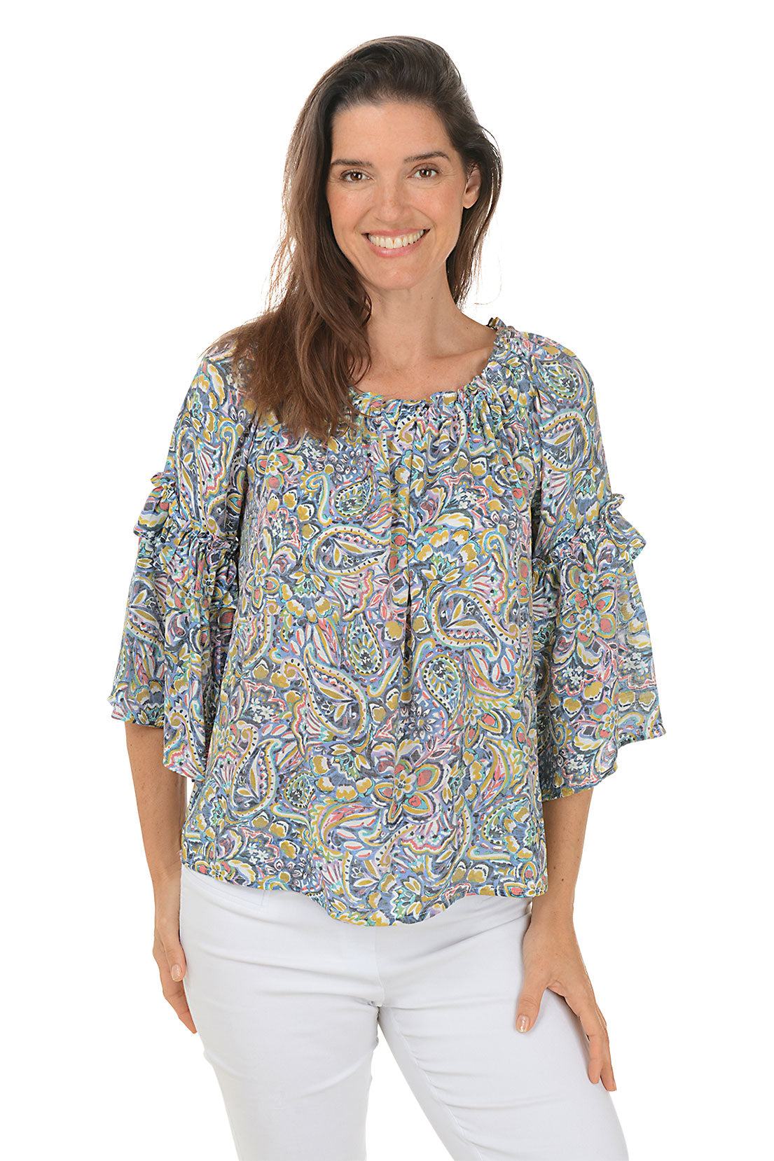 A front shot of a model wearing a floral paisley ruffled bell sleeve blouse with a scoop neck, in a multi-colored pattern. She is also wearing white pants.