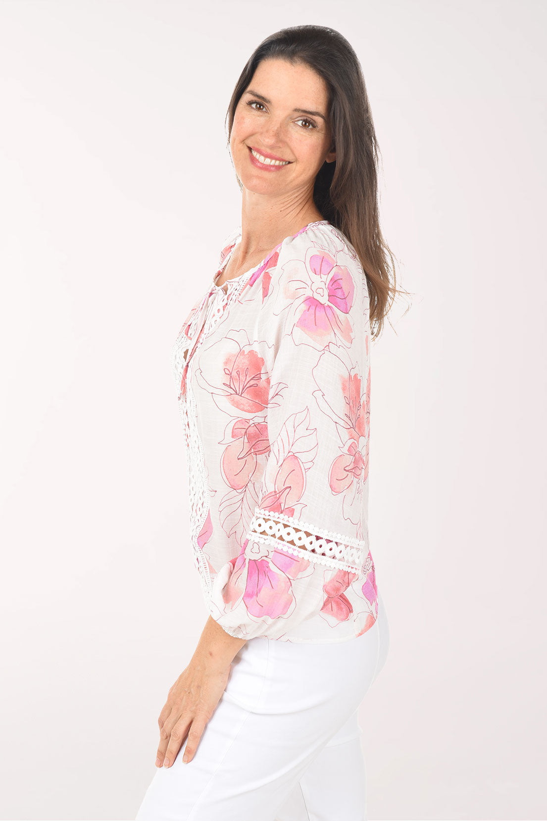 Woman wearing a white blouse with pink floral patterns on a white background