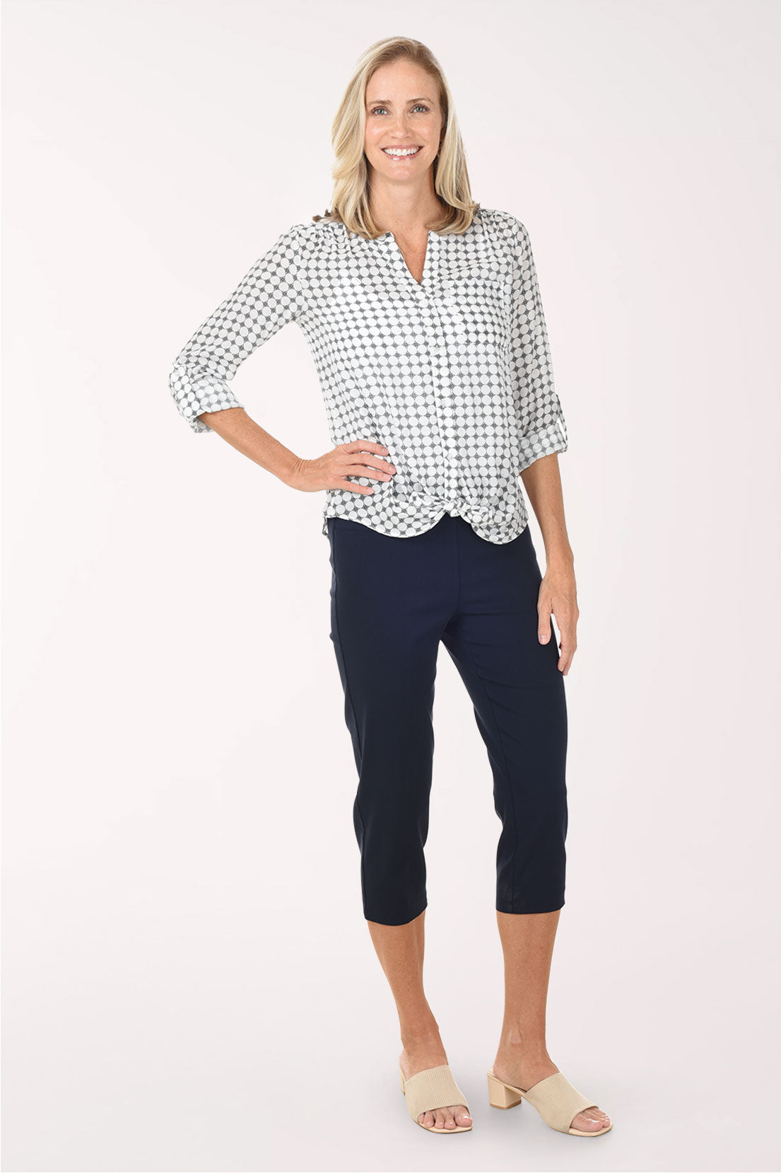 Woman wearing a navy and white checkered blouse with navy pants on a white background