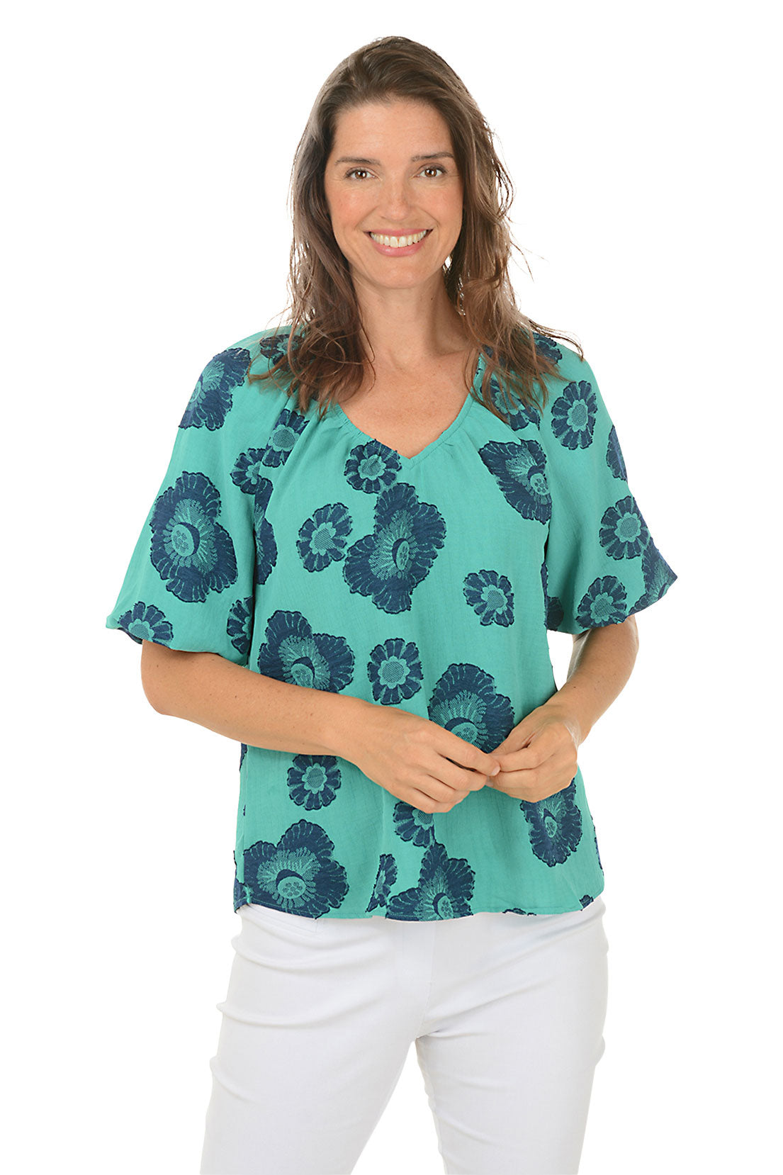 A front shot of a woman wearing a green and blue floral jacquard blouse with puffed sleeves and a V-neck.