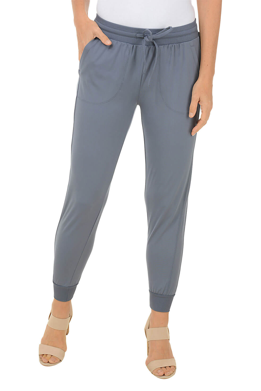 A front shot of a model wearing a pair of grey ankle-length jogger pants with an elastic waistband and adjustable drawstring, featuring front patch pockets with a zippered coin pocket, flat back, relaxed fit through the leg, and rib-knit cuffs at the ankle.