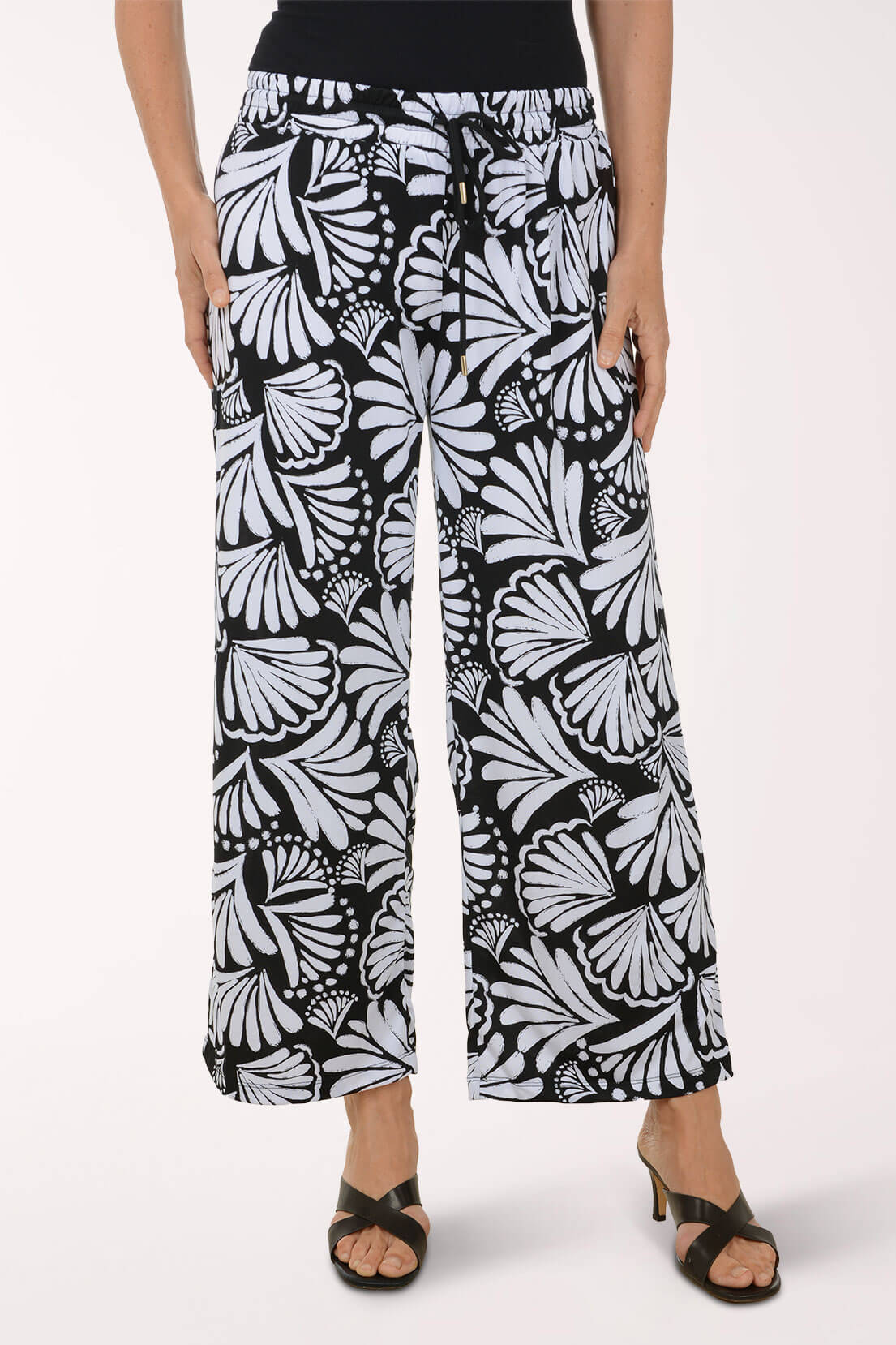 Person wearing black and white patterned pants on a white background