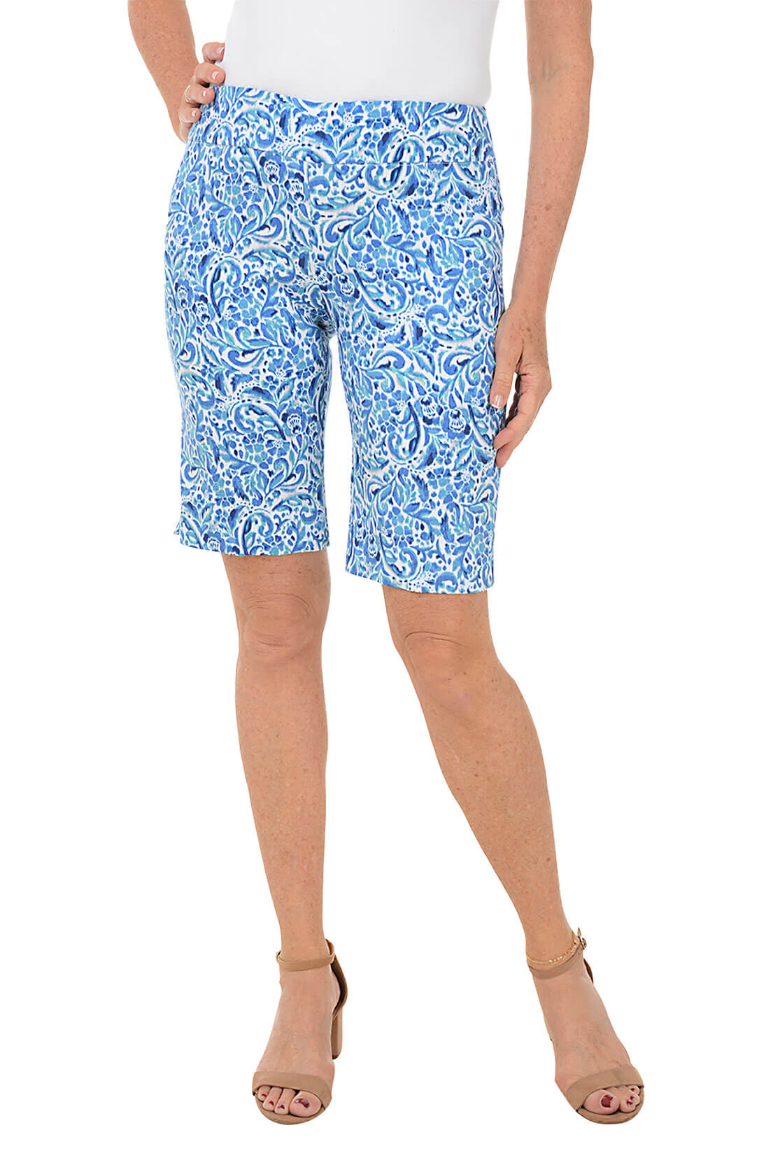 A front shot of a model wearing blue floral nebula pull-on bermuda shorts with a white top, standing against a white background.