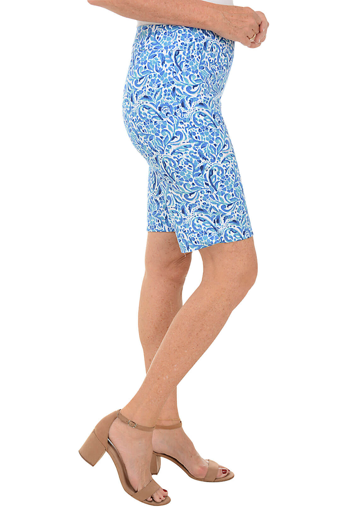 A side shot of a model wearing blue floral nebula pull-on bermuda shorts with a white top, standing against a white background.