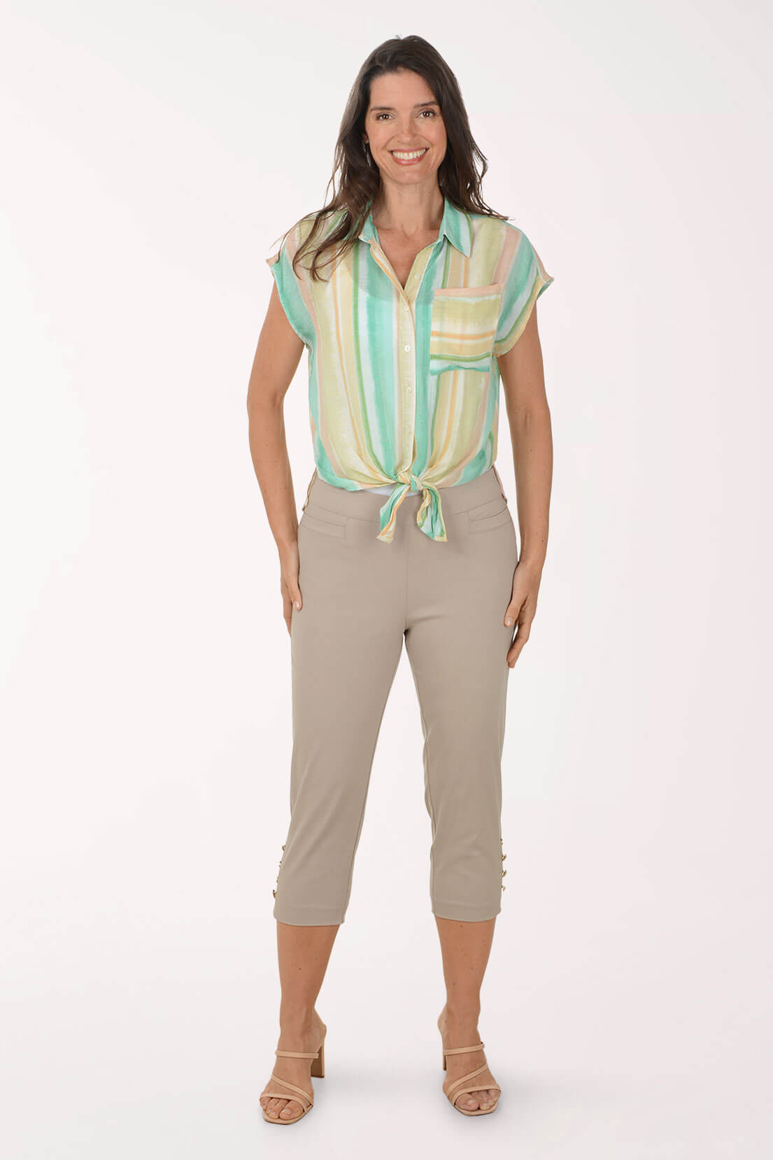 Woman wearing a sleeveless striped shirt and beige pants on a white background