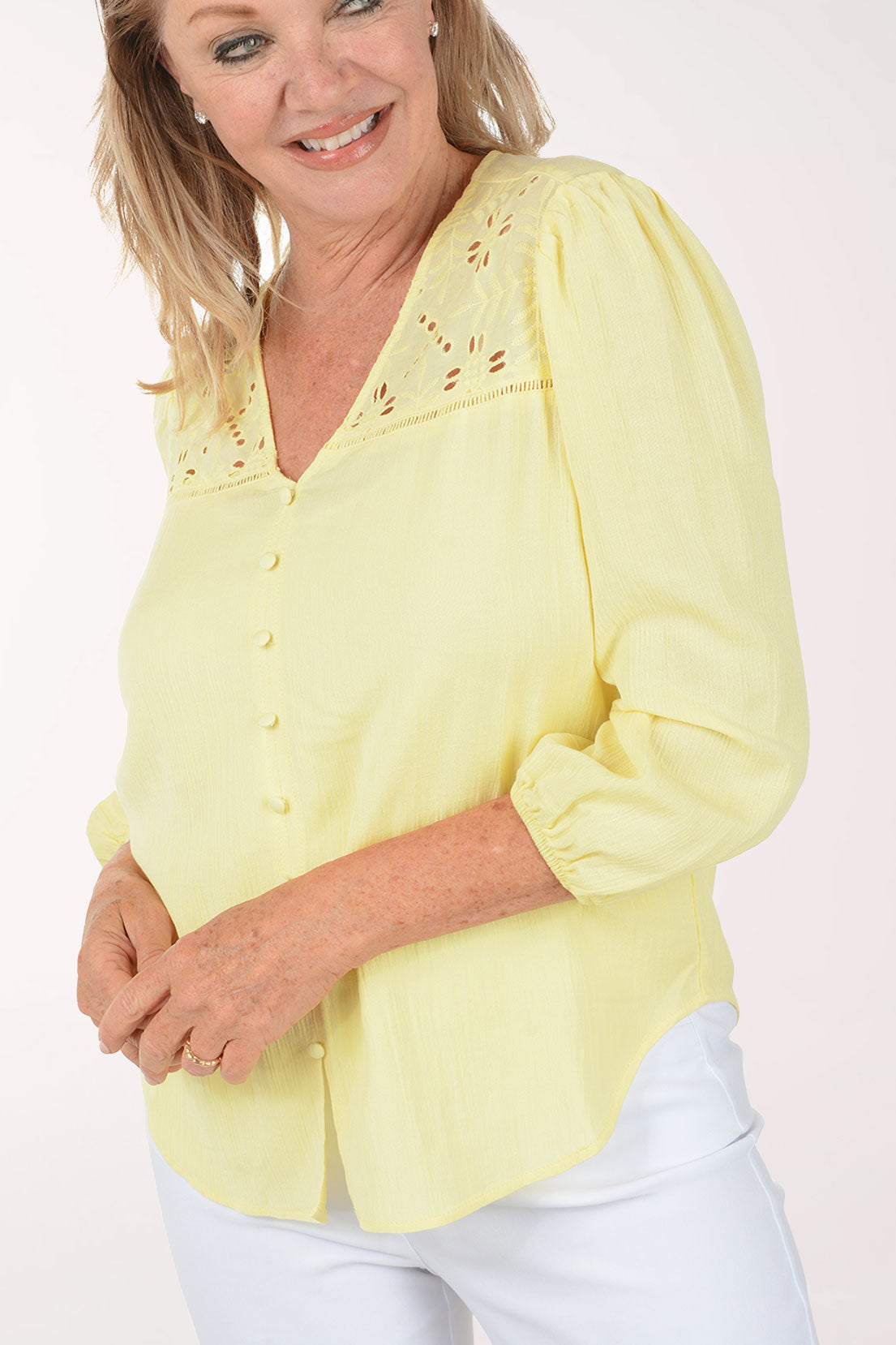 Woman wearing a yellow blouse with floral embroidery on a white background