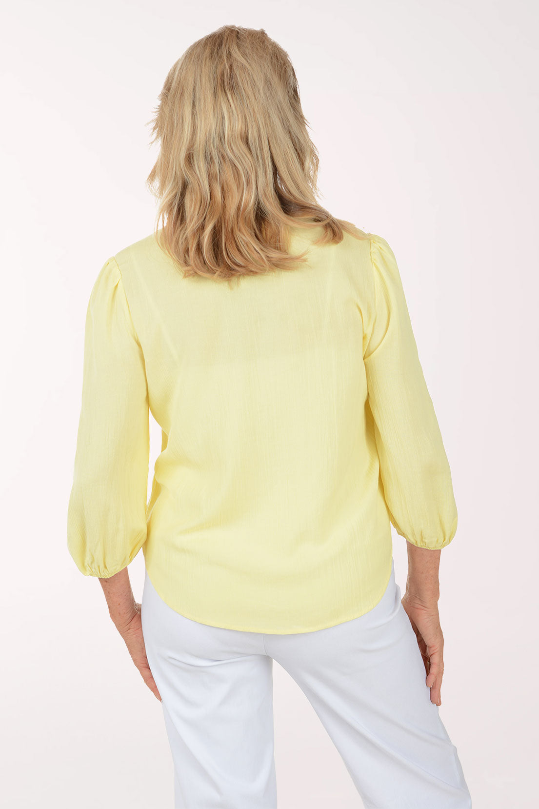 Woman wearing a yellow blouse with floral embroidery on a white background