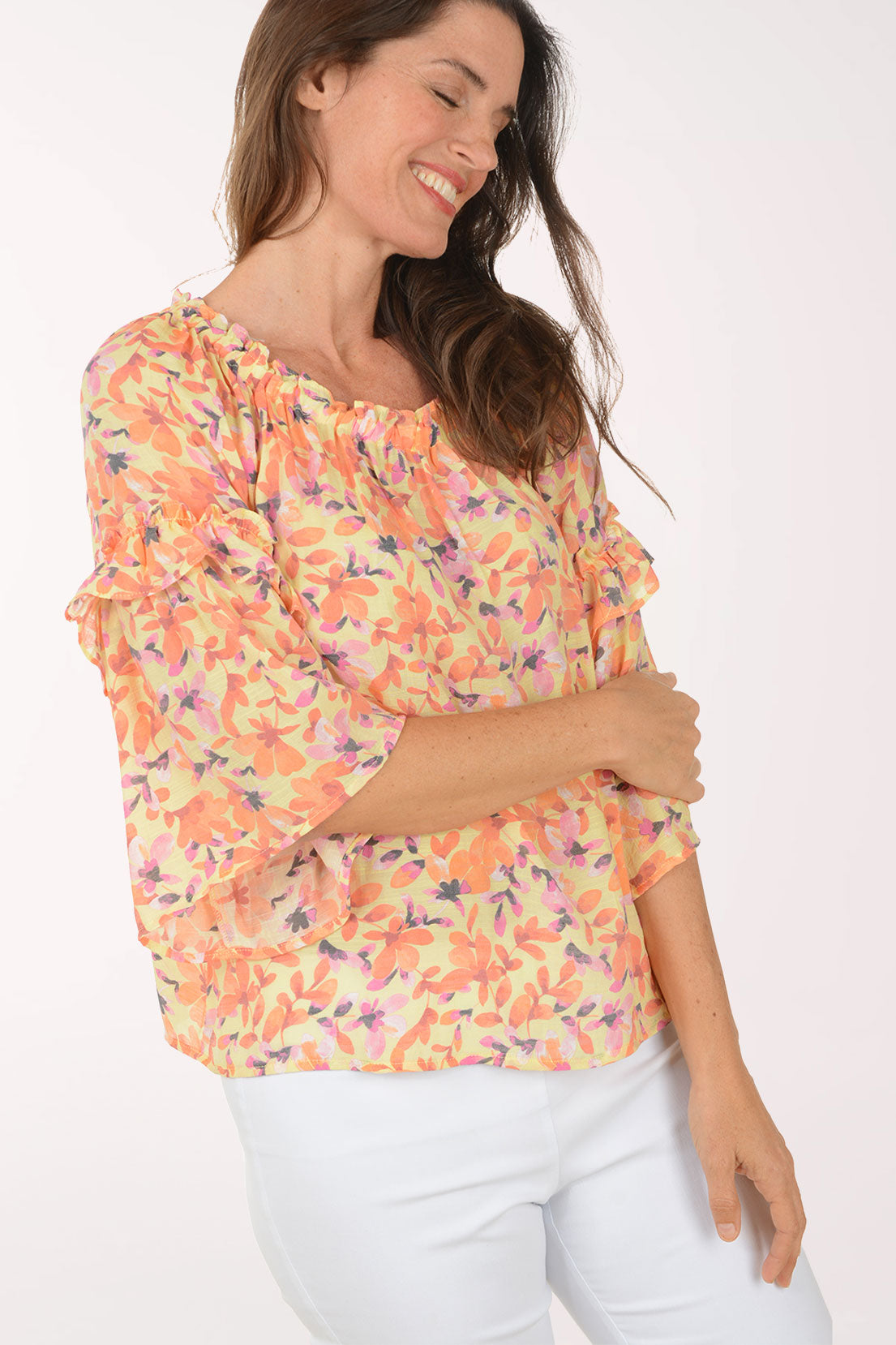 Woman wearing a colorful floral blouse with ruffled sleeves on a white background