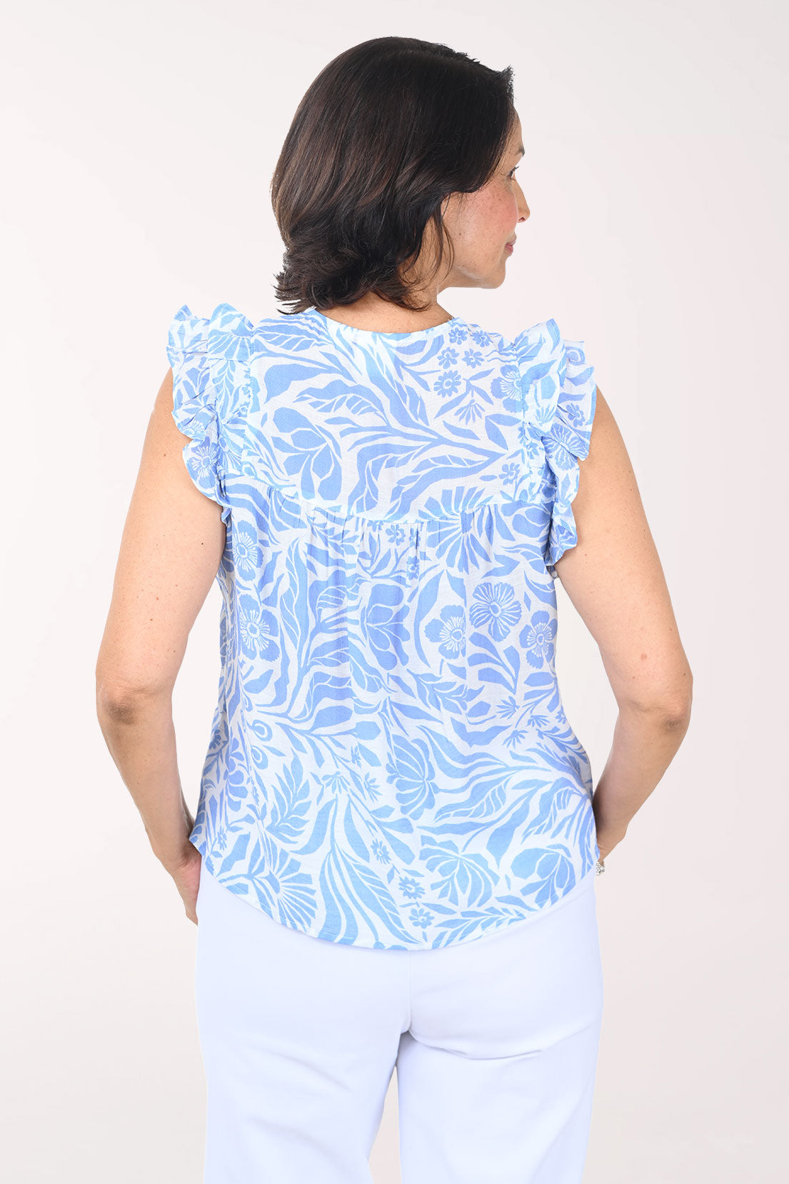 Woman wearing a blue floral sleeveless top against a white background