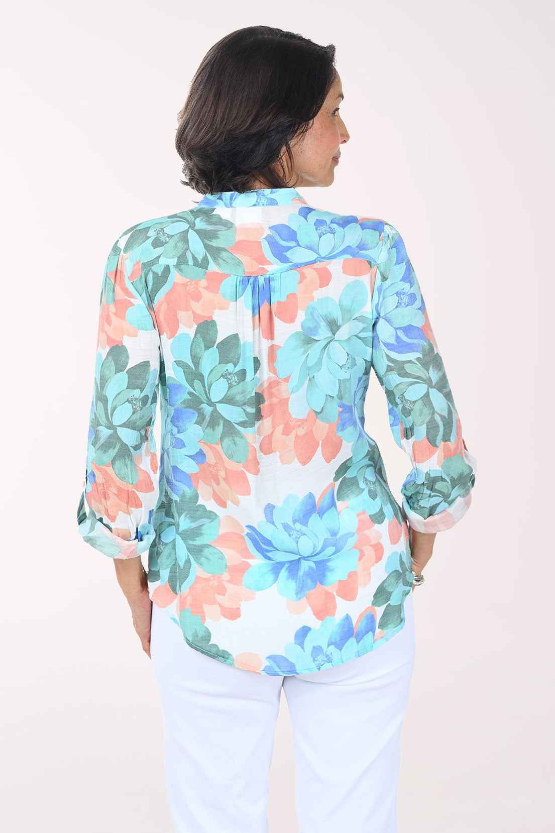 Woman wearing a colorful floral blouse against a white background