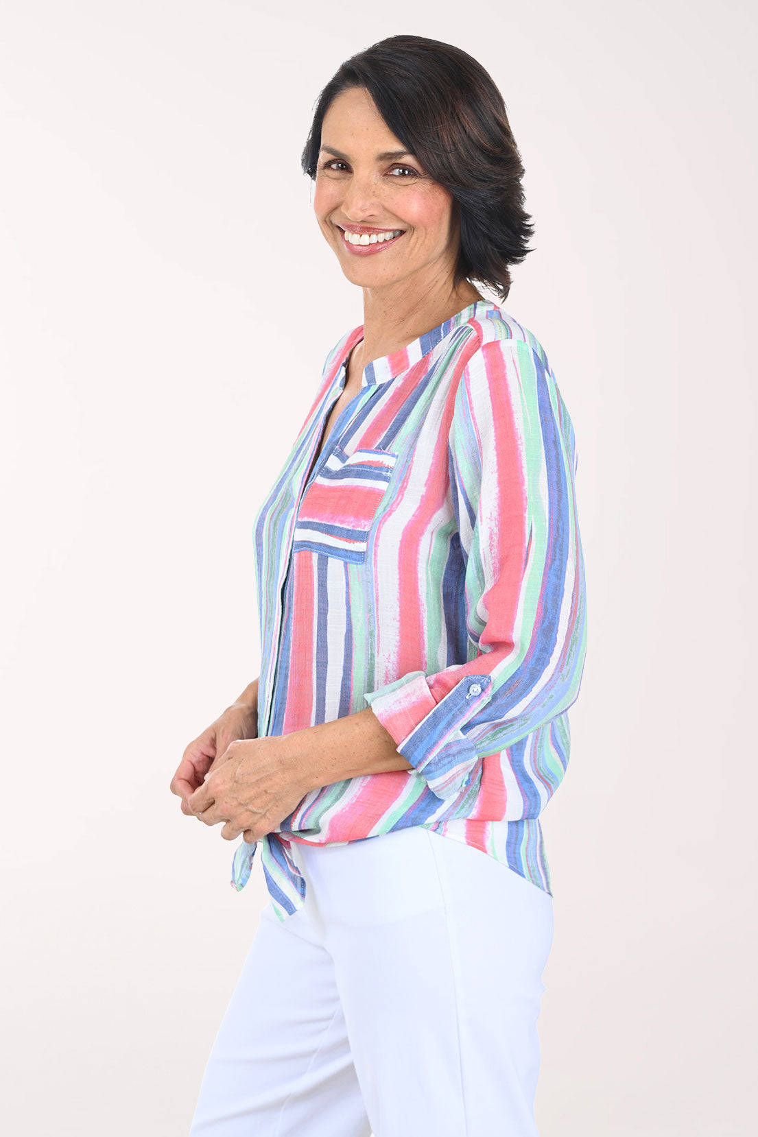 Woman wearing a colorful striped shirt and light pants on a white background
