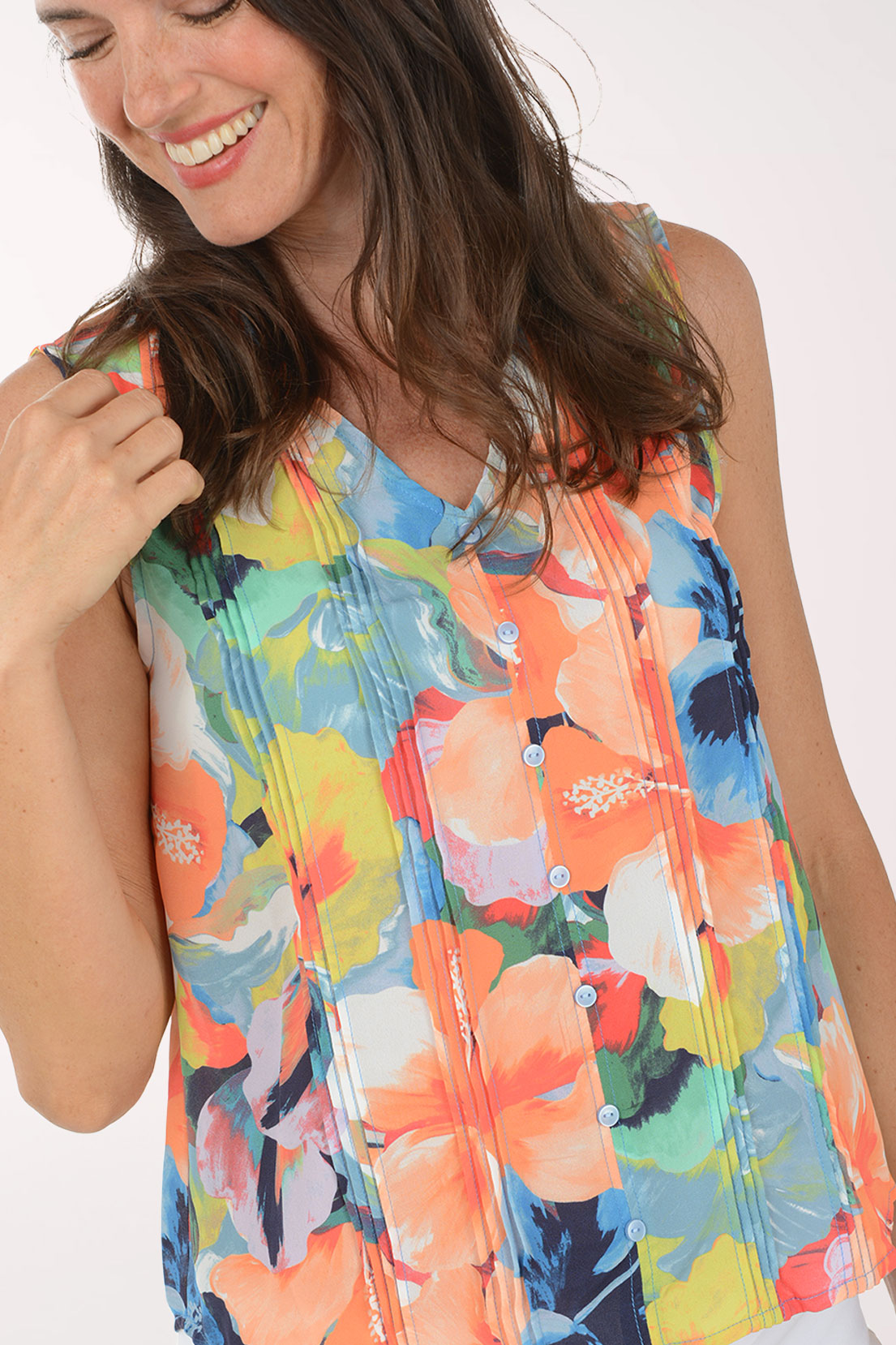 Woman wearing a colorful floral sleeveless top against a white background