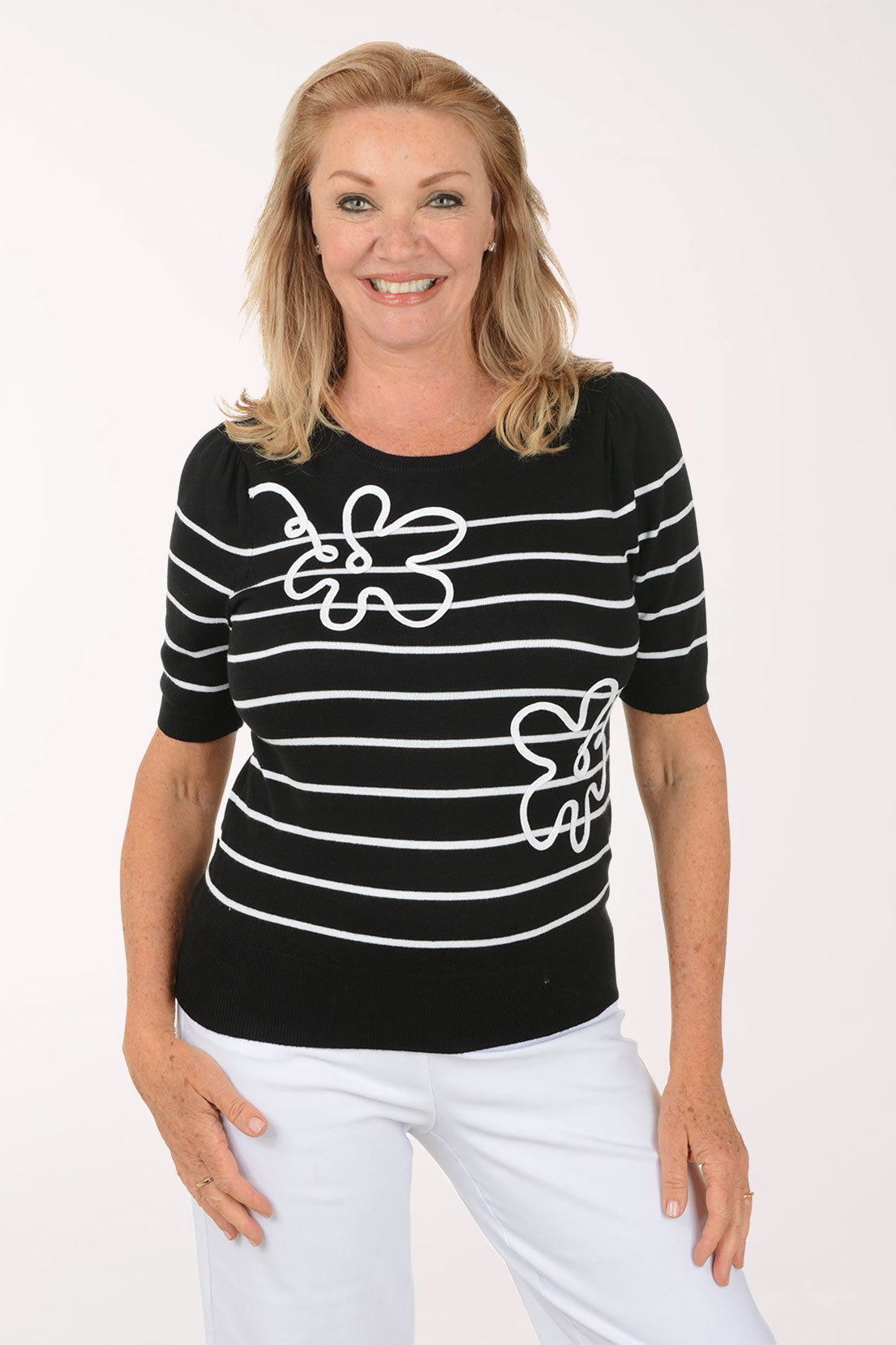 Woman wearing a black and white striped shirt with butterfly designs on a white background