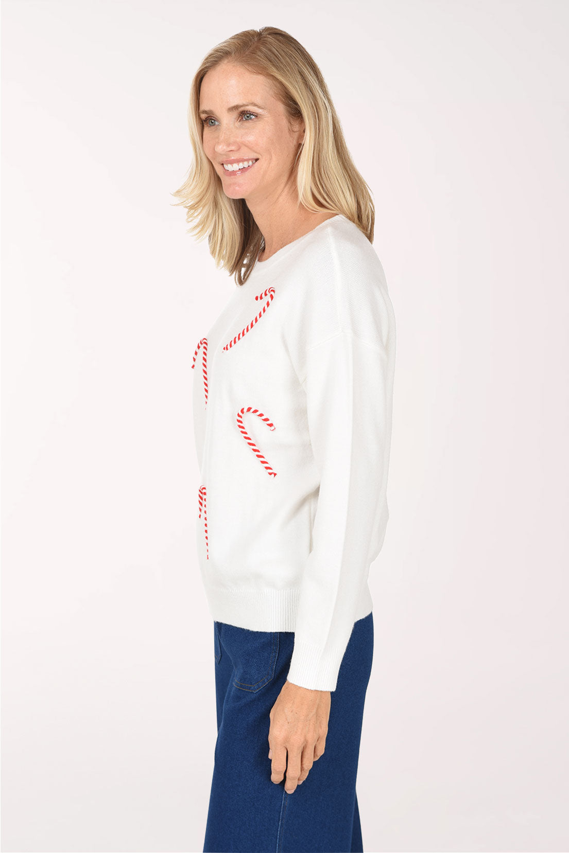 Side view of the ivory Candy Cane Sweater showing the drop shoulder, candy canes on the front and ribbed hem