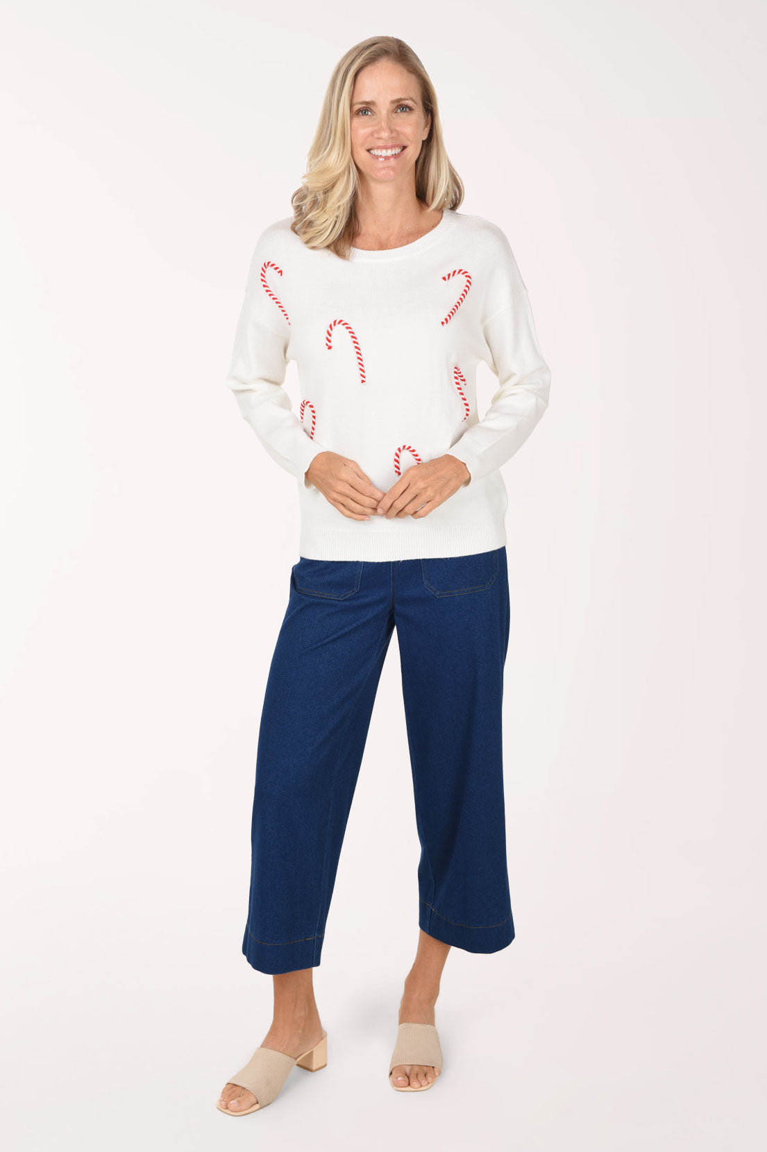 A full length view of medium wash wide leg cropped jeans styled with a white candy cane sweater.