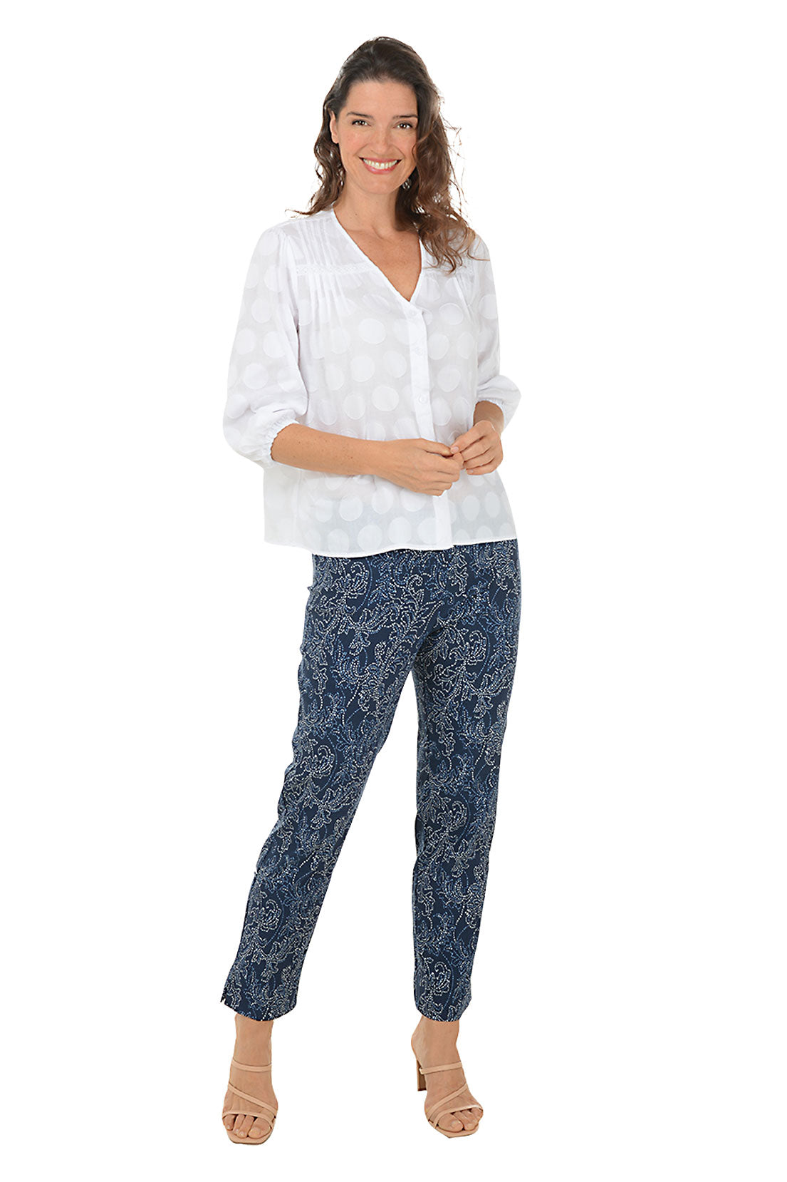A full length shot of a model with a pair of pull-on ankle pants with a floral pattern, featuring an elasticized waistband, flat front and back, tummy control lining, and side slits on the hemline.