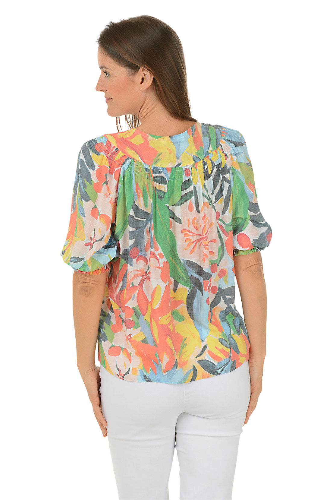A back shot of a woman wearing a blue and white floral crochet v-neck blouse with short flutter sleeves and straight hemline, paired with jeans.