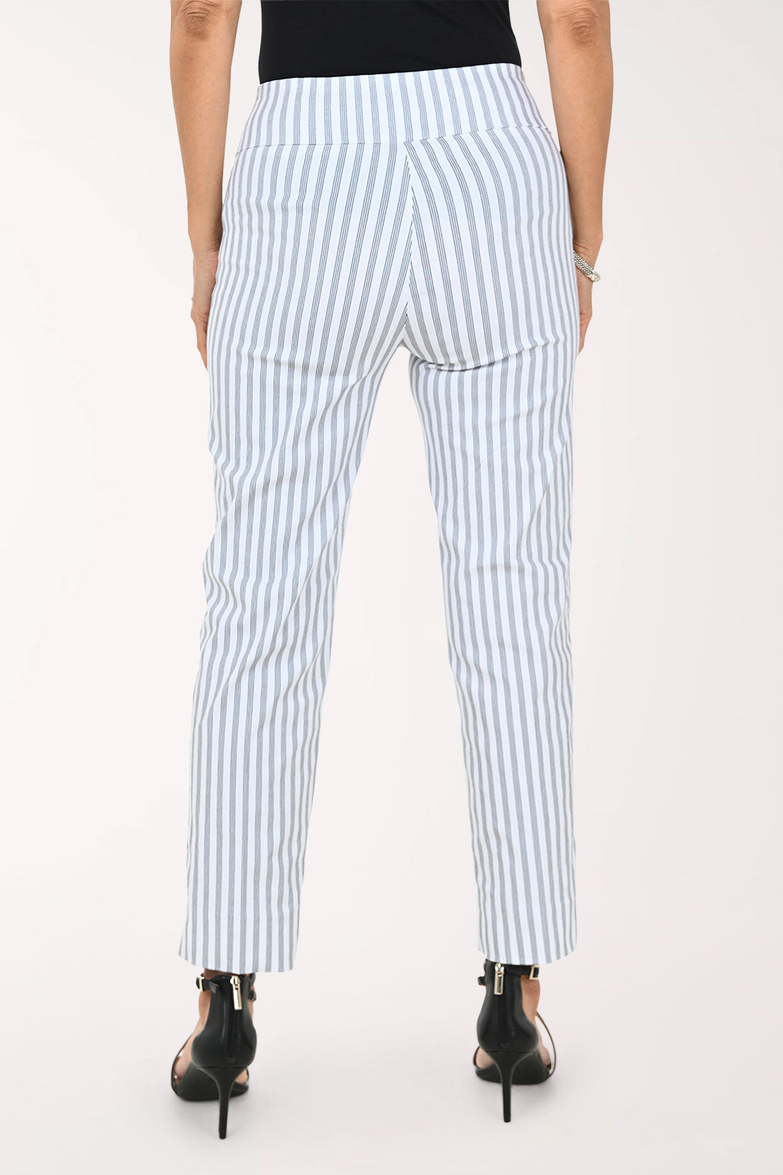 A model wearing light blue and white vertically striped cropped trousers, paired with a black top and black strappy high-heeled sandals, against a plain white studio background.