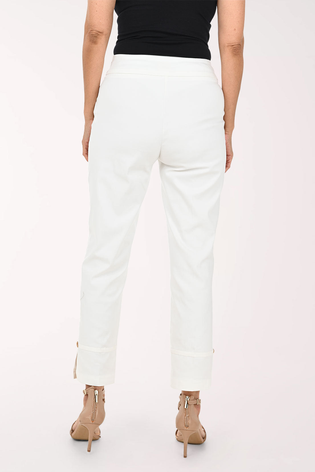 White cropped ankle pants with rolled cuffs and small side zippers, shown on a model wearing beige strappy heels against a plain light background.