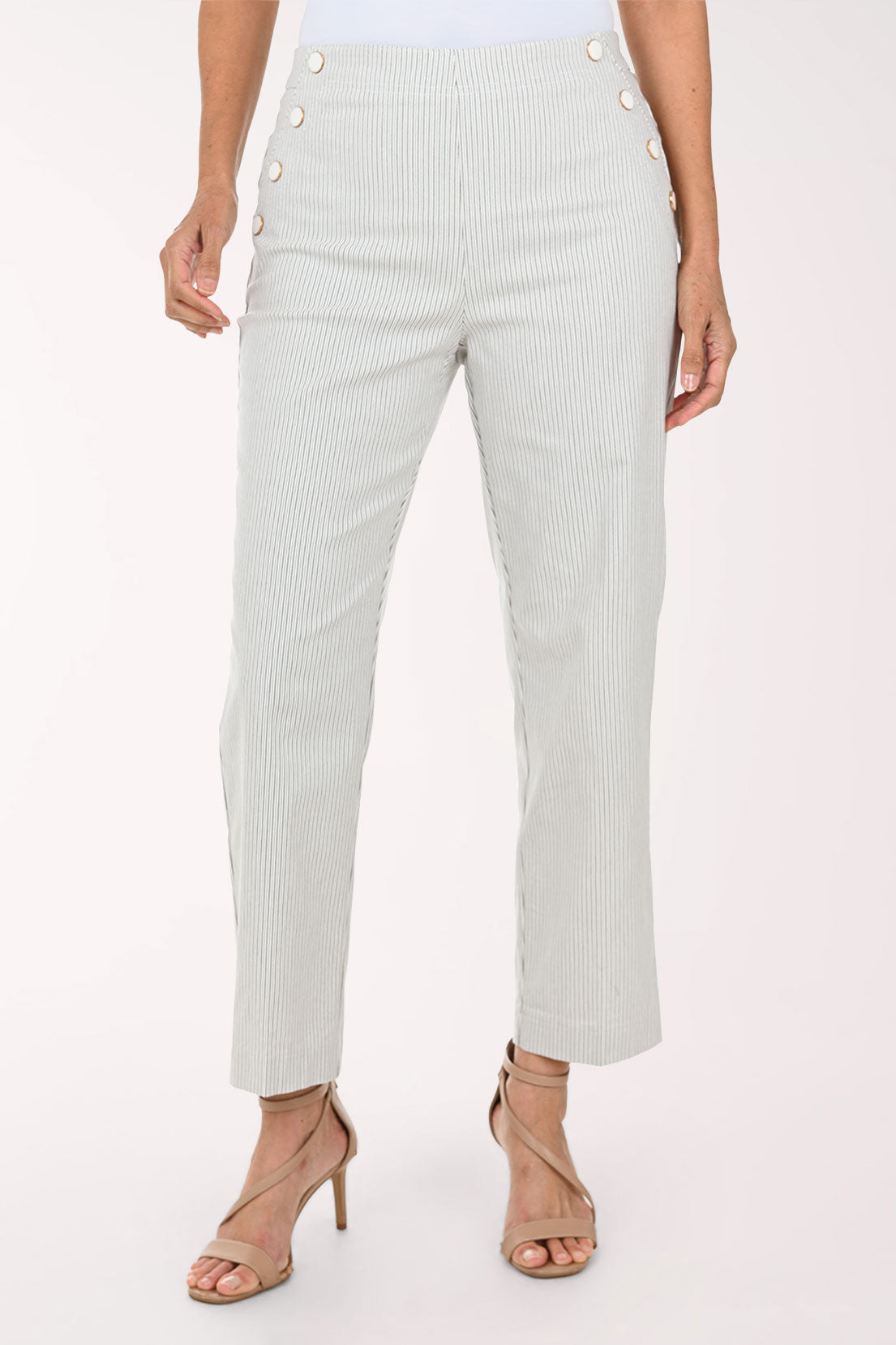 A model wearing light sage green pinstriped trousers with decorative gold buttons on the sides, paired with beige strappy high-heeled sandals against a plain white background.