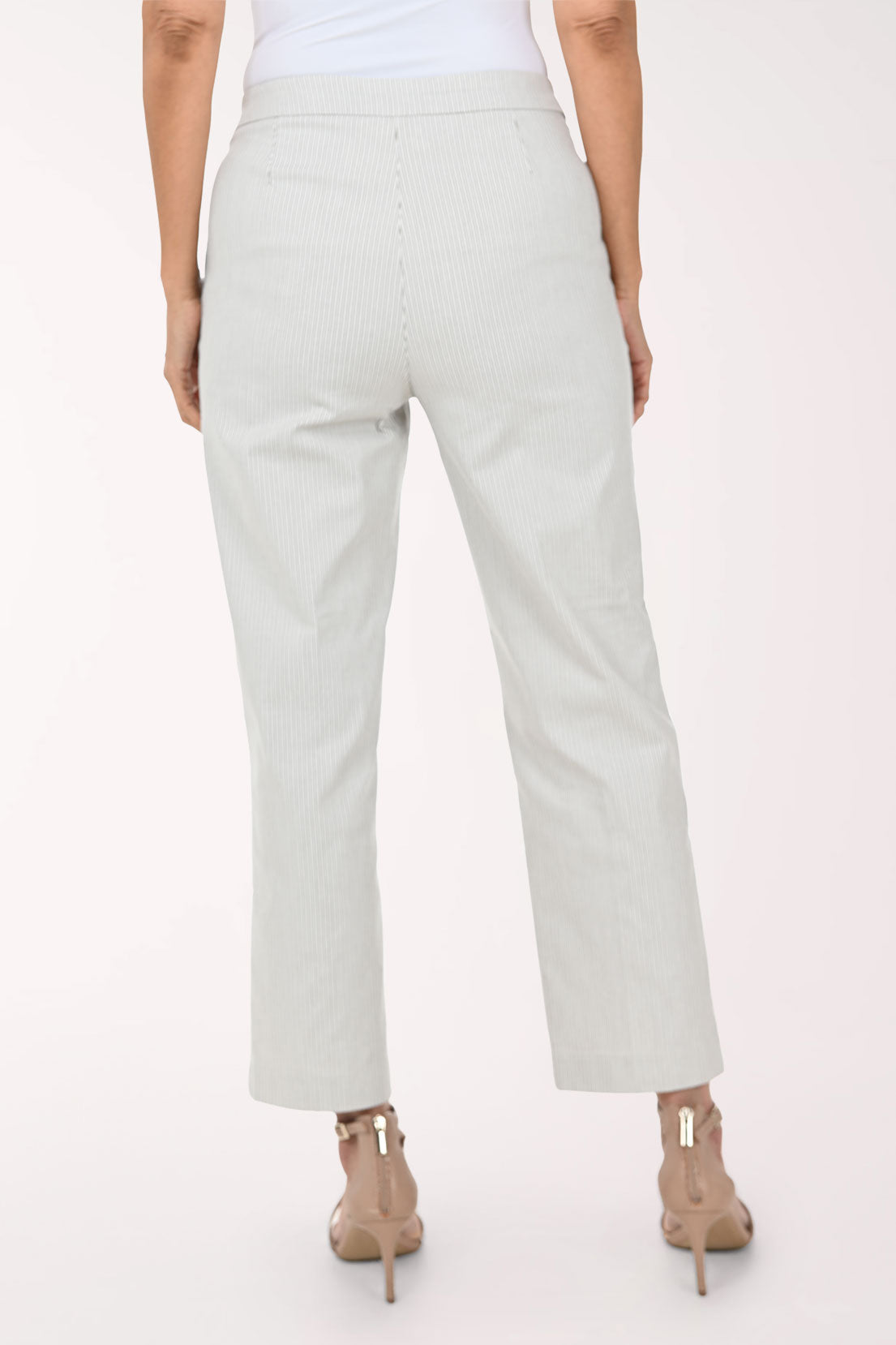 A model wearing light sage green pinstriped trousers with decorative gold buttons on the sides, paired with beige strappy high-heeled sandals against a plain white background.