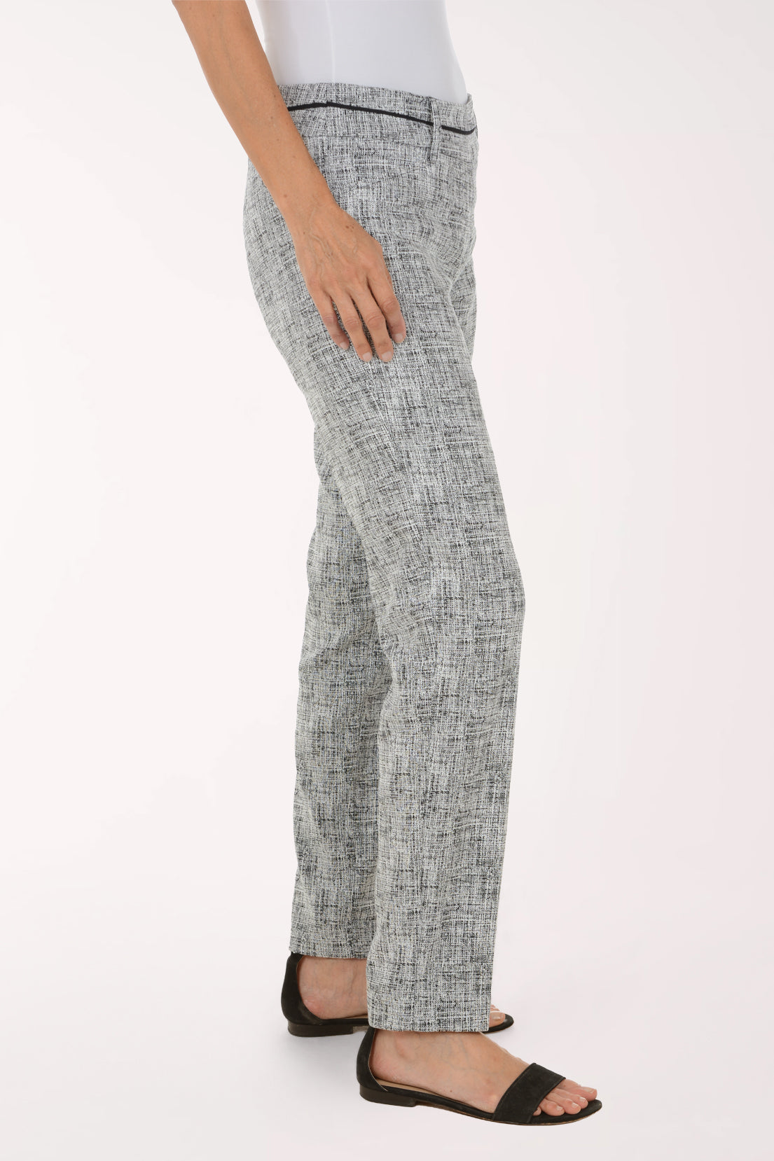 A model wearing a pair of slim-fit trousers in a gray and white textured tweed pattern, paired with black slide sandals against a plain white studio background.