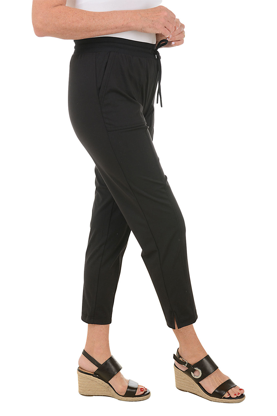 A side shot of a model wearing a Ankle-length active pant with drawstring waistband, front patch pockets, and pintuck detail on the front leg. Hemline with side slits.