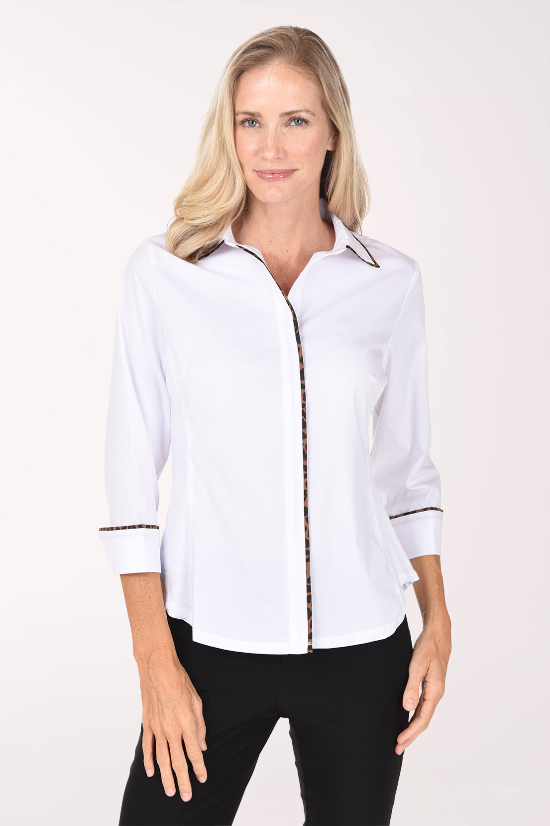 A woman wearing a white button-up shirt with animal print trim along the collar, placket, and rolled cuffs, paired with black pants, against a plain light background.