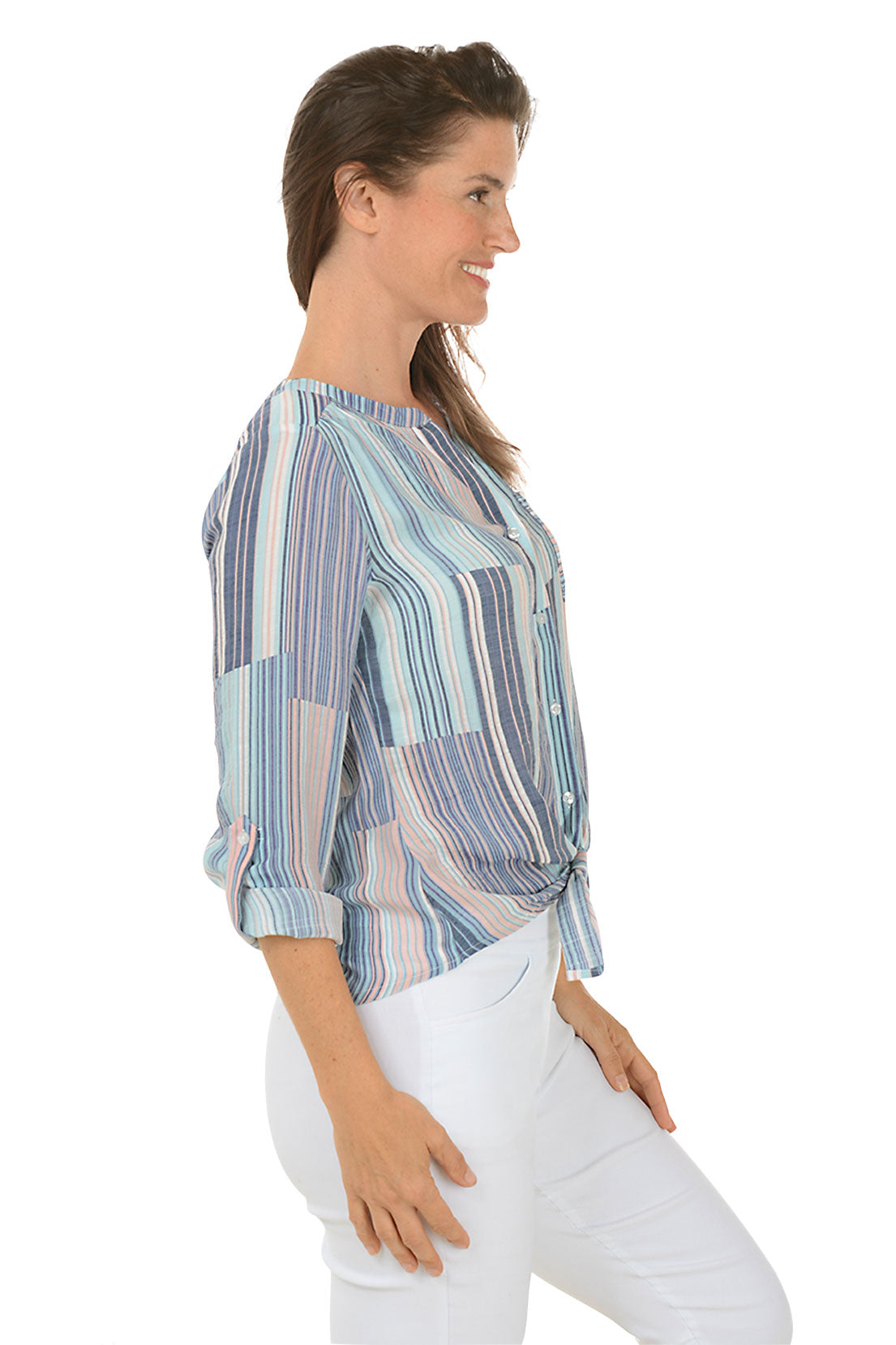 A side shot of a woman wearing a striped button-front blouse with a mandarin collar and long sleeves, tied at the front, paired with white pants.