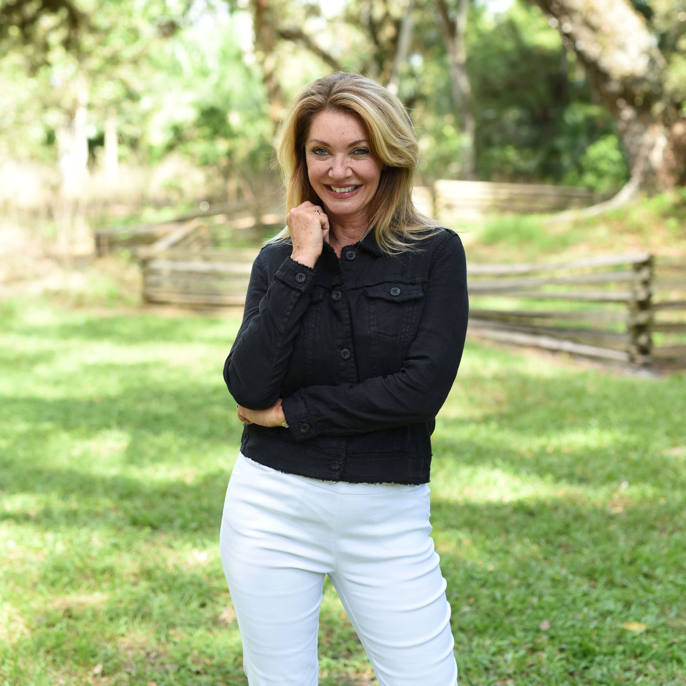 Model in black jacket standing in the park.