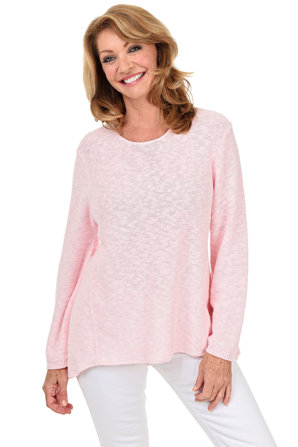 A woman wearing a long sleeve light pink cotton scoop neck sweater, with a seam down the front and white pants.