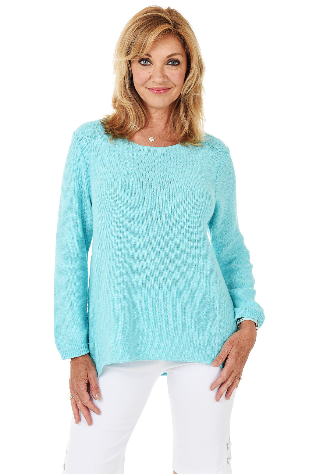 A woman wearing a long sleeve aqua cotton scoop neck sweater, with a seam down the front and white pants.