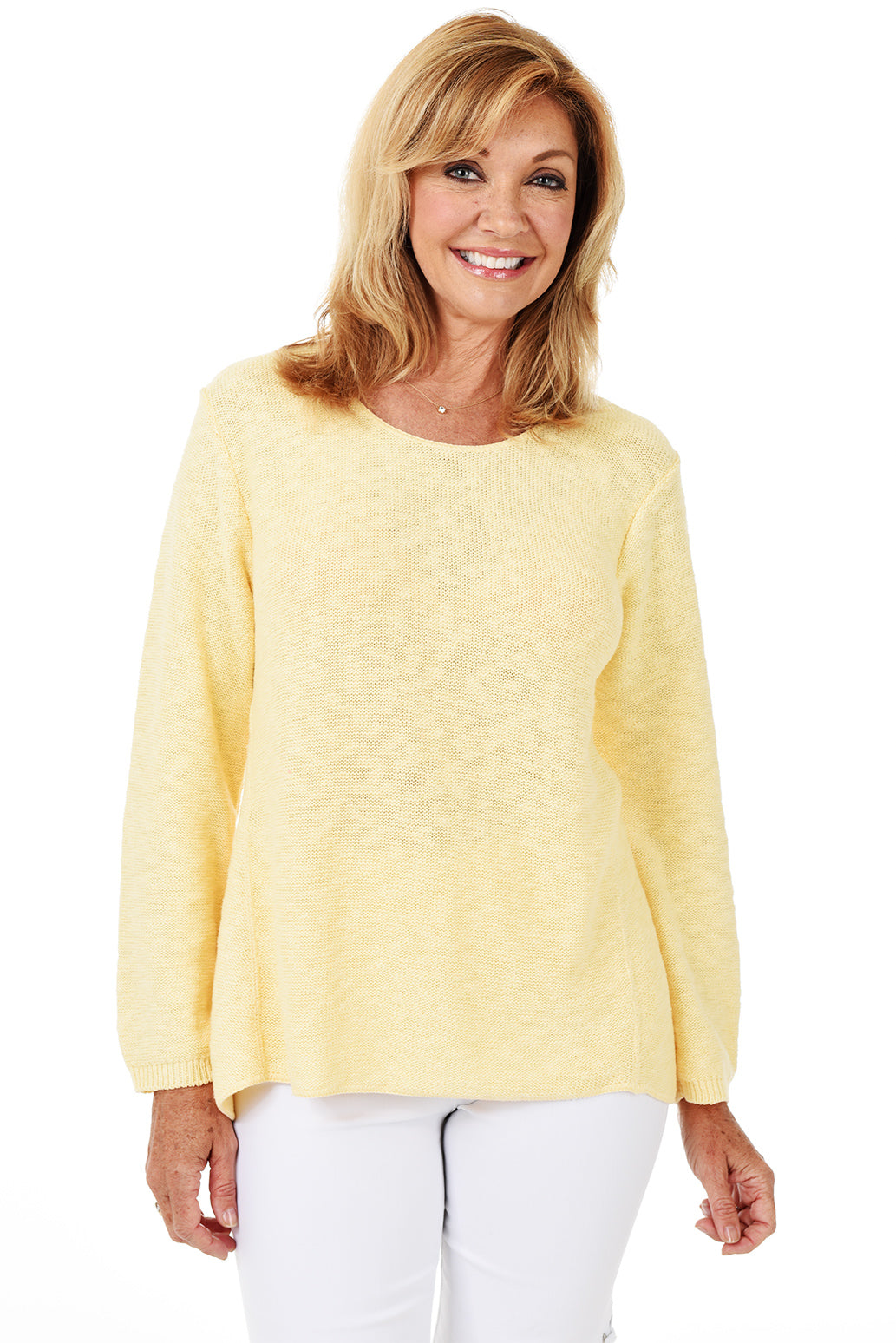 A woman wearing a long sleeve yellow cotton scoop neck sweater, with a seam down the front and white pants.