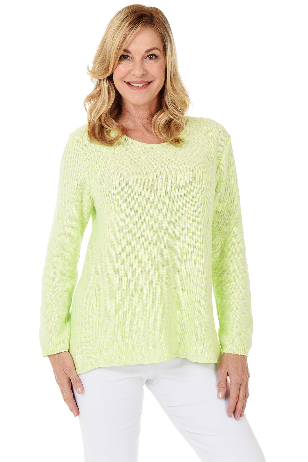 A woman wearing a long sleeve green cotton scoop neck sweater, with a seam down the front and white pants.