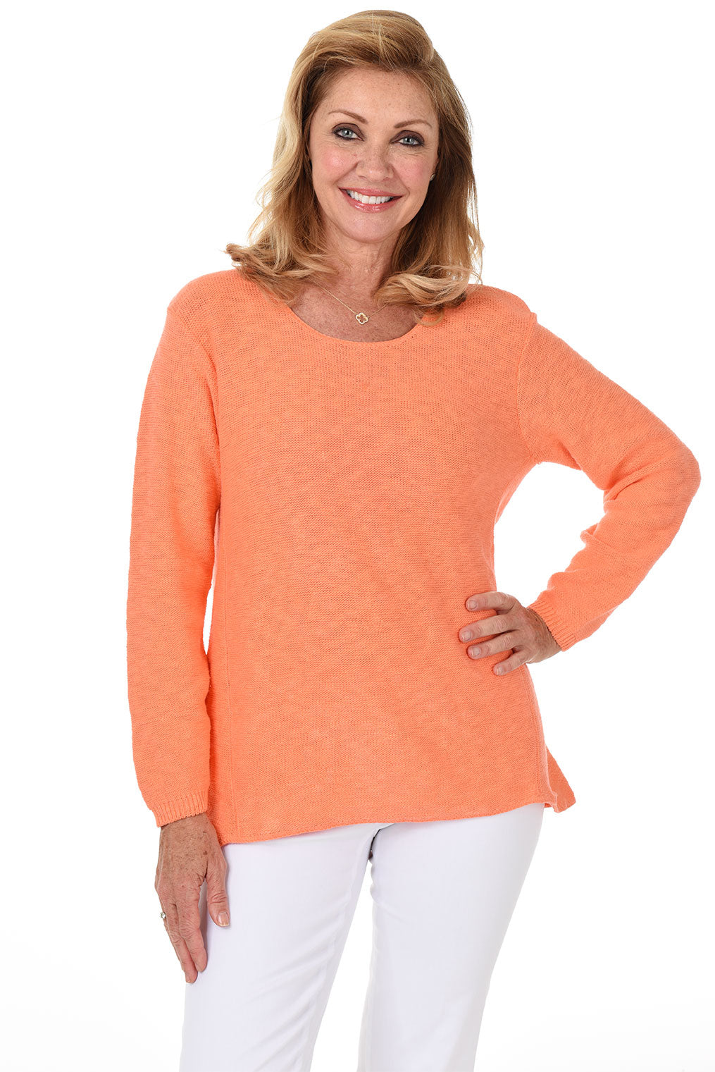A woman wearing a long sleeve mandarin orange cotton scoop neck sweater, with a seam down the front and white pants.