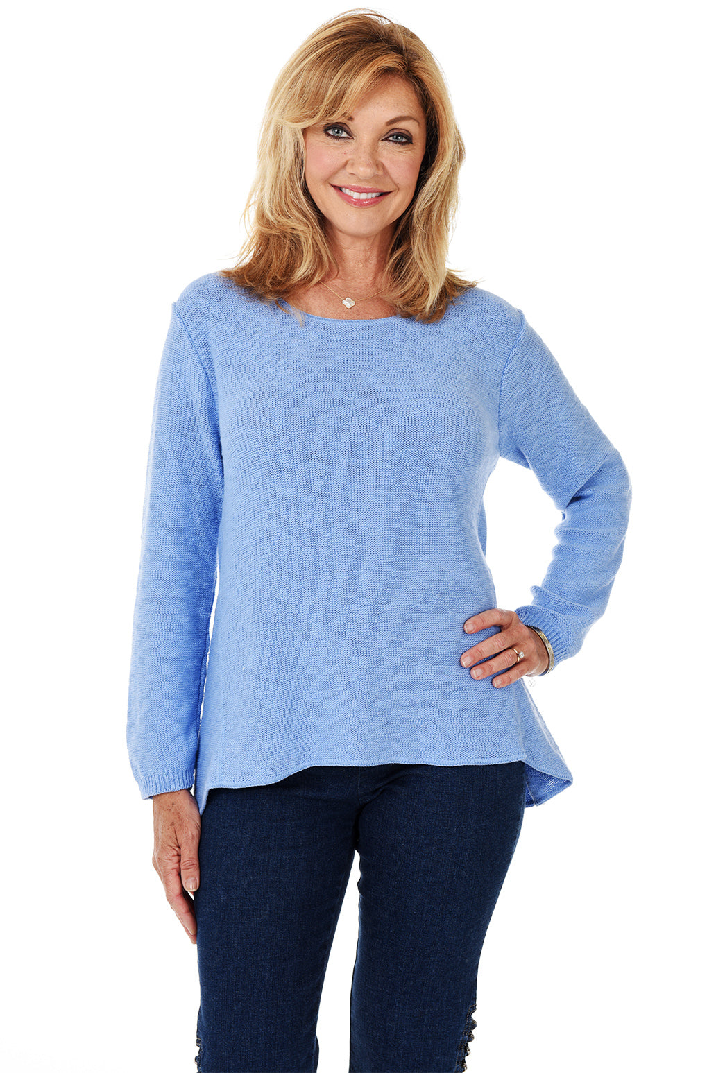 A woman wearing a long sleeve periwinkle cotton scoop neck sweater, with a seam down the front and white pants.