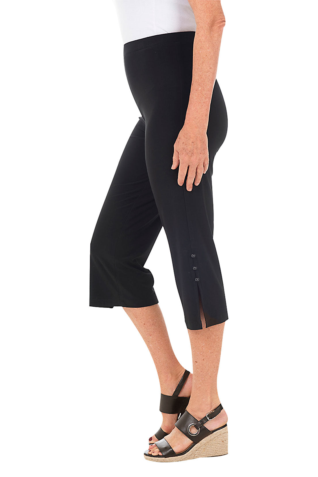A model wearing black wide-leg capri pants with side button embellishments. Side shot.