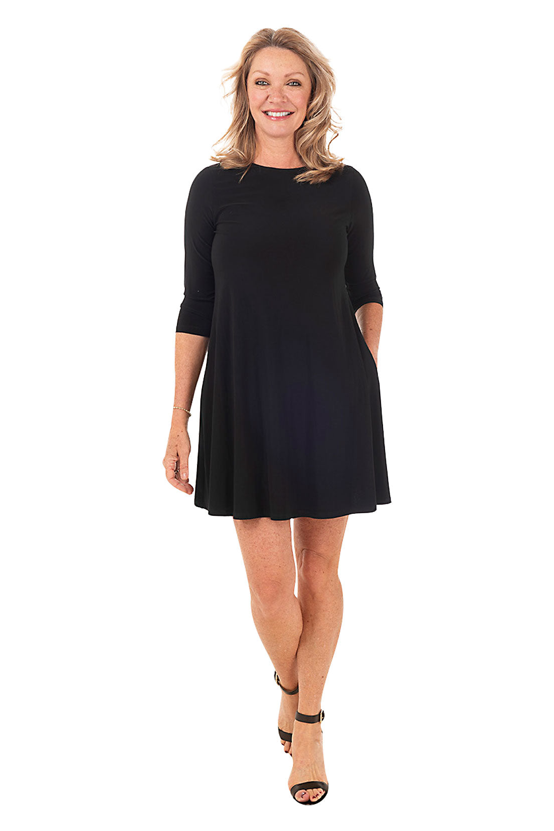 A model wearing a long sleeve black dress with a scoop neckline, dual side pockets, and a straight hemline.