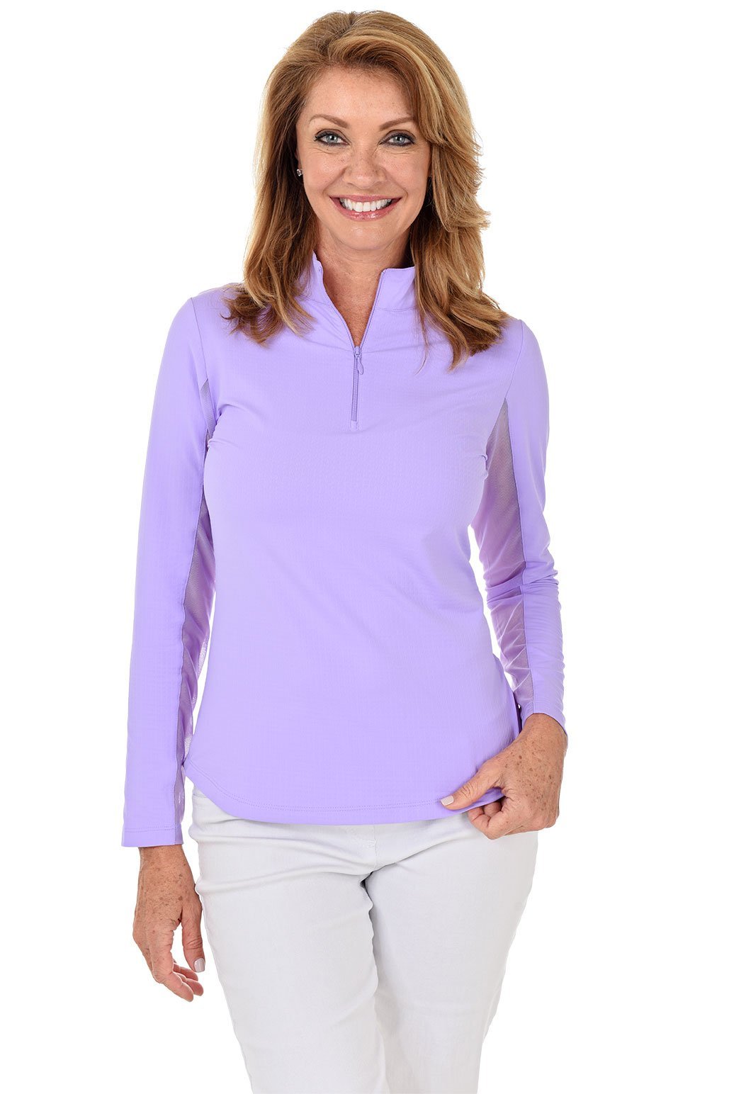 A woman smiling and wearing a long-sleeved lavender sun shirt with a mock-neck collar and a pair of white pants.