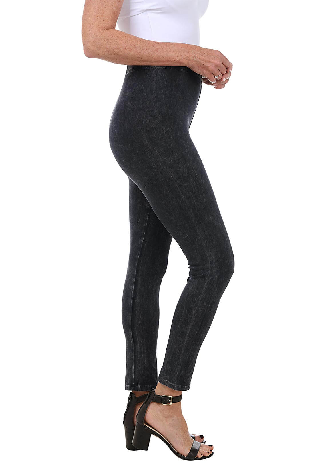 A side shot of a model wearing a pair of black mineral wash leggings with an elastic waistband, ankle-length design, and front rise positioned at 9 1/2 inches.