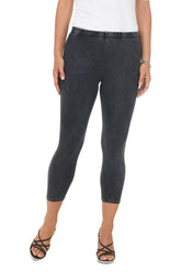 A front shot of a model wearing a pair of black mineral wash capri leggings with an elastic waistband, made from stretchy cotton fabric.