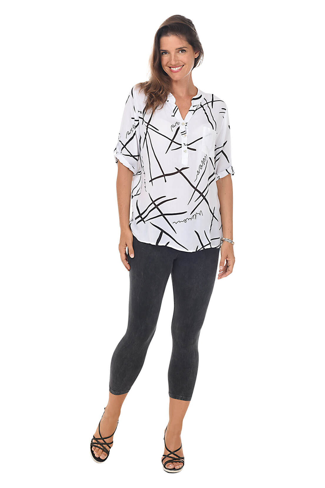 A full length shot of a model wearing a pair of black mineral wash capri leggings with an elastic waistband, made from stretchy cotton fabric.