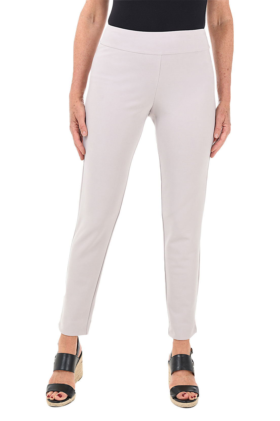 A front shot of a model wearing a pair of white microfiber pull-on ankle pants with an elastic waistband, displayed on a model wearing black top and heels