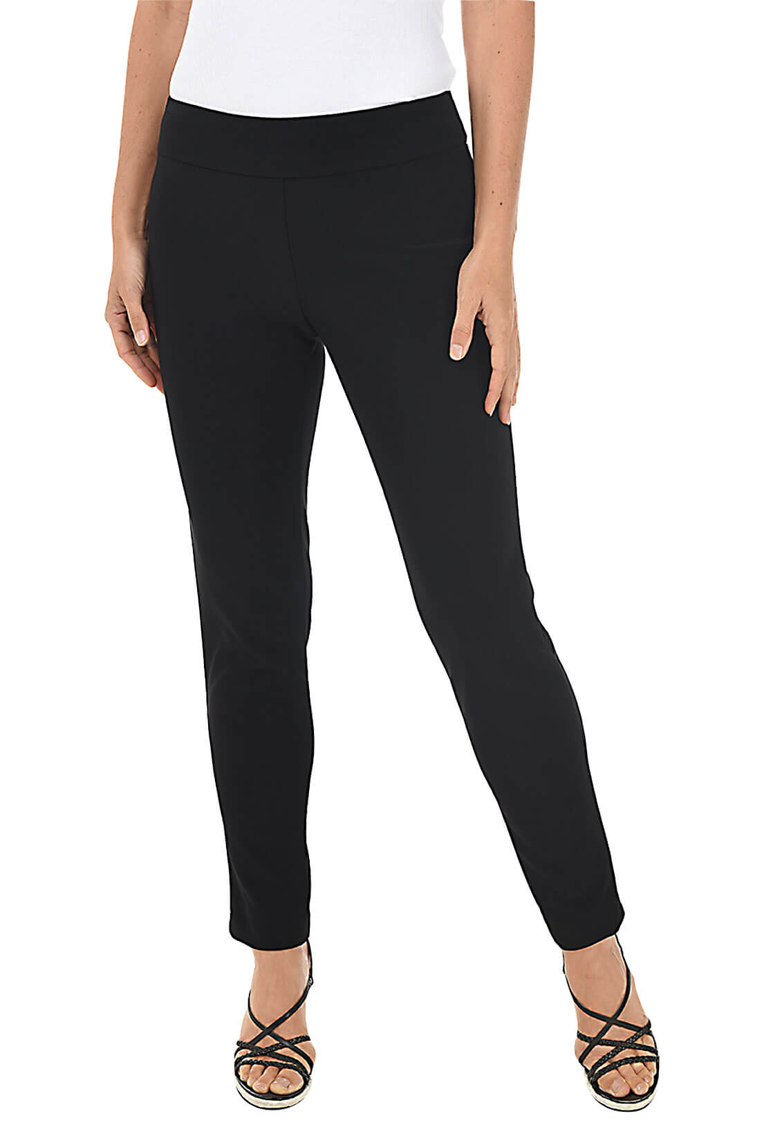 A front shot of a model wearing a pair of black microfiber pull-on ankle pants with an elastic waistband, displayed on a model wearing black top and heels
