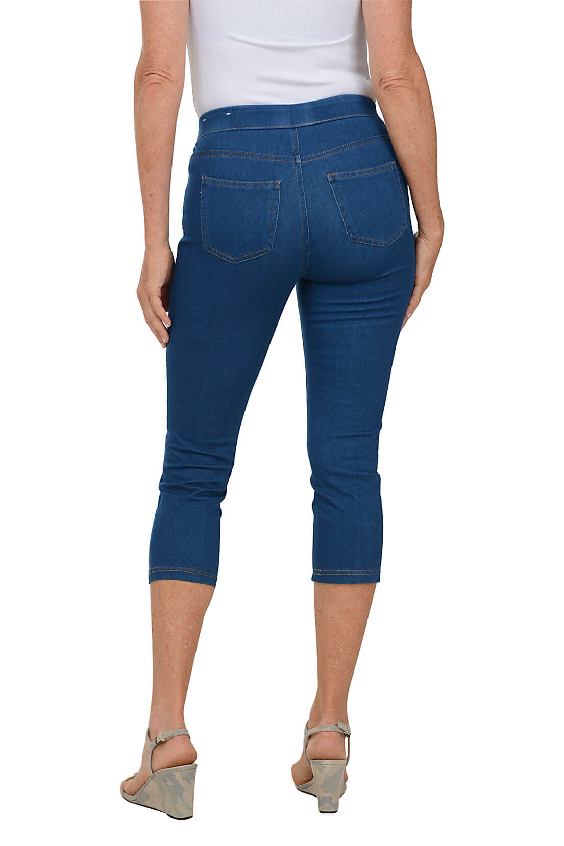 A back shot of a model wearing a pair of blue pull-on capri-length jeggings with an elastic waistband.