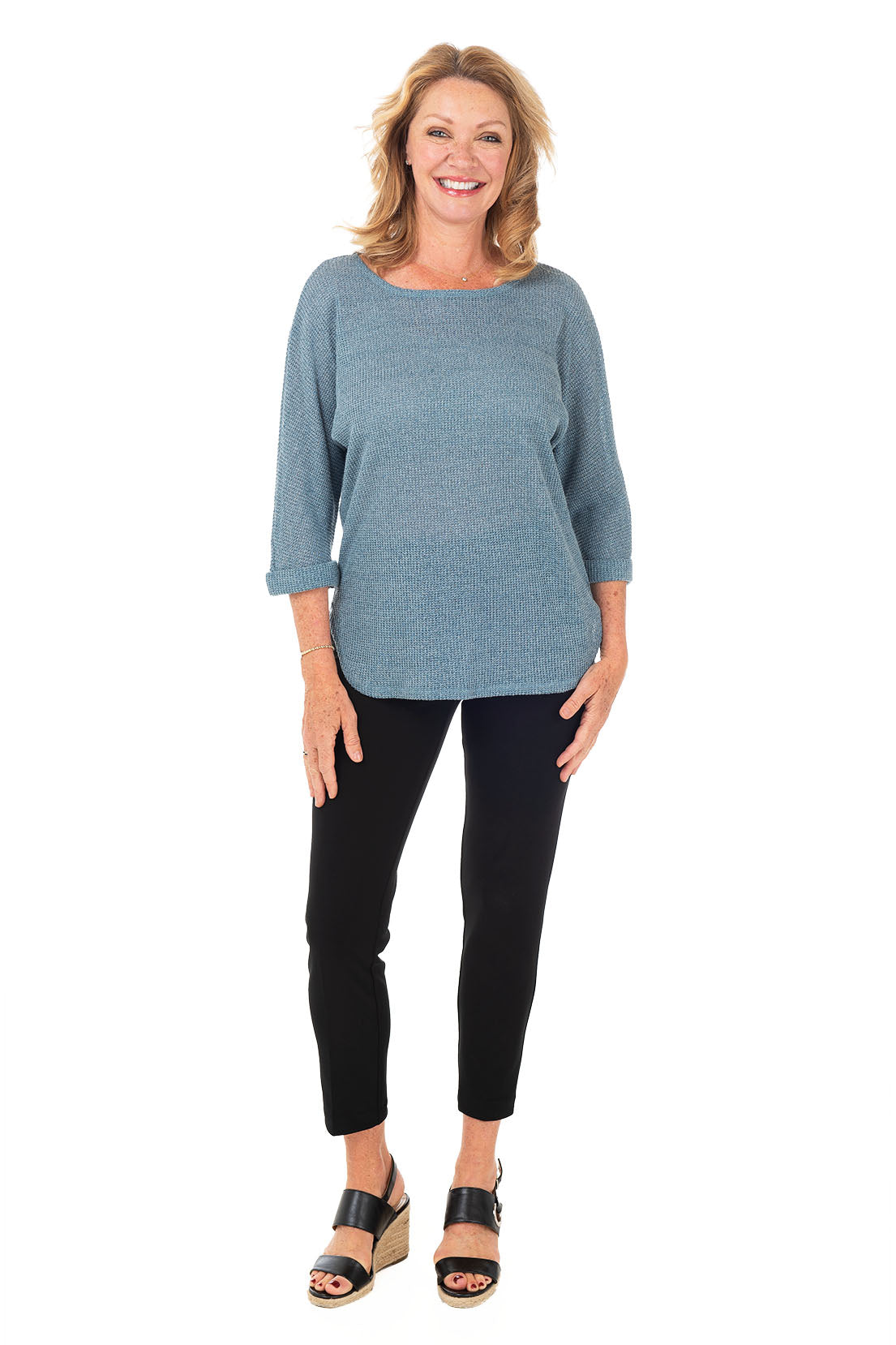 A model wearing black pull-on ankle length dress pants with an elasticized waist, flat front and back, and straight leg design. Full length shot.