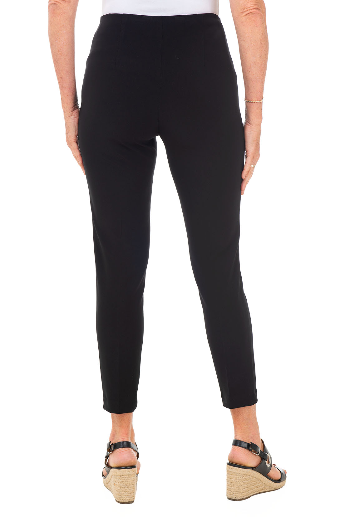 A model wearing black pull-on ankle length dress pants with an elasticized waist, flat front and back, and straight leg design. Back shot.