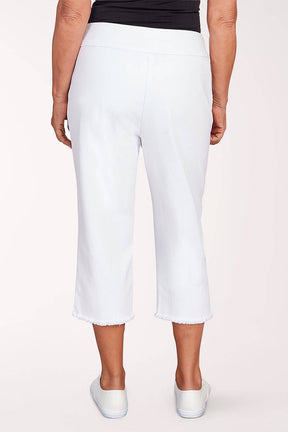 A woman wearing white denim capri pants and white sneakers against a light pink background. Back shot