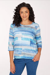 Woman wearing a 3/4 sleeve blue brushstroke top.